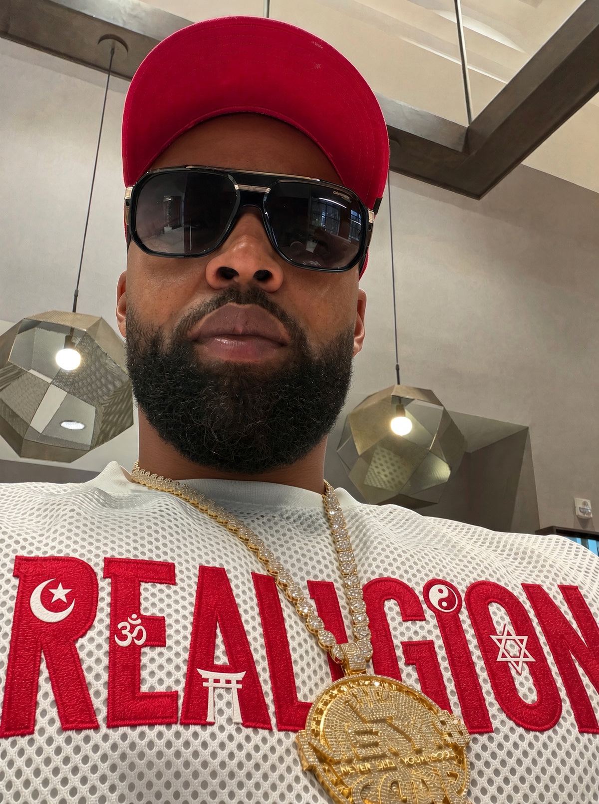 REALIGION founder in red cap and sunglasses wearing the REALIGION mesh jersey and gold chain